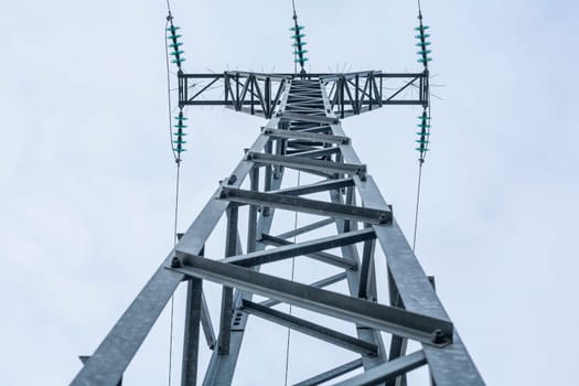 High voltage power pylons against blue sky. Low view