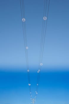 Power line wires over blue sky on vertical perspective. Closeup