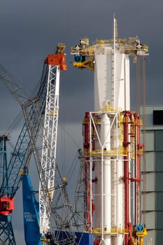 Drilling mast of a new drill ship surrounded by cranes