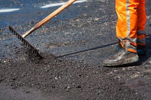 Manual worker leveling asphalt with a rake