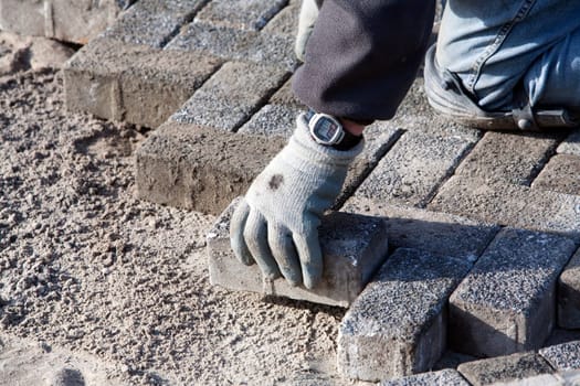 Close up of the hand and knee of a paver