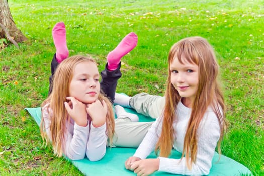 Photo of two girls sitting on grass in summer