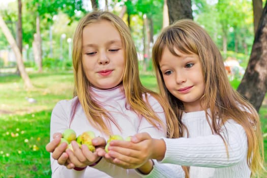 Photo of two girls with apples in summer