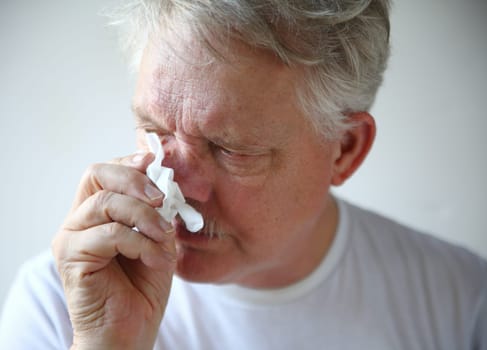 A man with the flu or a cold wipes his runny nose.