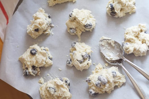 Spooning out batter into biscuit shapes on parchment paper