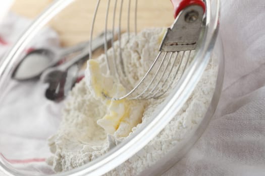 Using a pastry blender to incorporate butter into flour, vintage measuring spoons in background