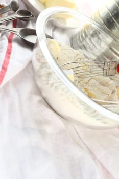 Glass mixing bowl and pastry blender with butter, flour, vintage sifter and old measuring spoons