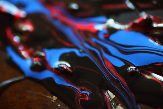 Shiny,  reflective surfaces of red, blue and black paints with bubbles