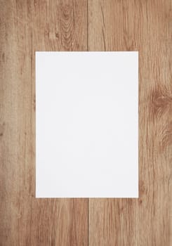 a white blank sheet of paper on a wooden background