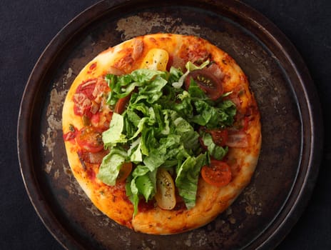 pizza topped with bacon, cherry tomatoes and Little Gem lettuce on an old pan