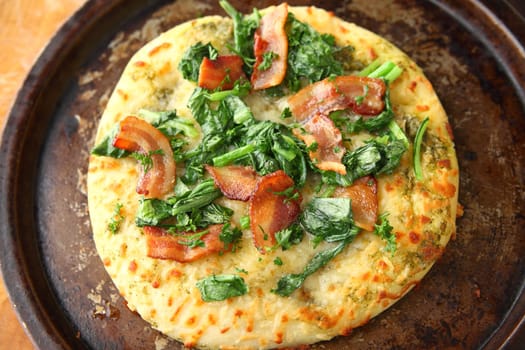 Pizza with bacon, leafy greens and parsley on an old pan