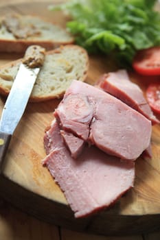 Slices of ham, lettuce, tomato, bread and a deli mustard