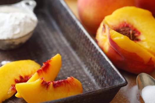 Fresh peaches sliced into a vintage pan with sugar and flour