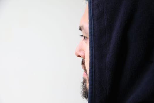 Profile of a young man wearing a black hooded jacket with copy space