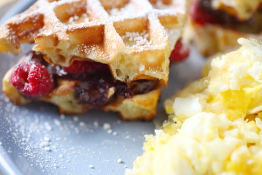 Waffles stufffed with fresh raspberries and chocolate spread with scrambled eggs