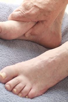 Senior man with his hand on one foot.
