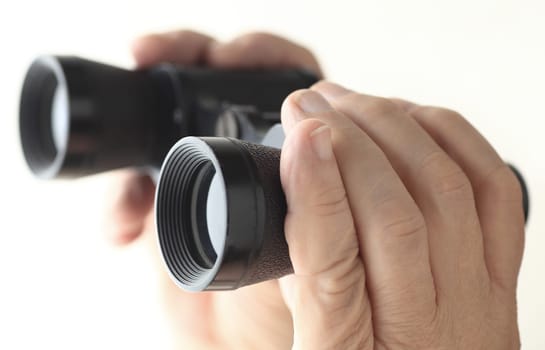 A man's hands holding an old pair of binoculars