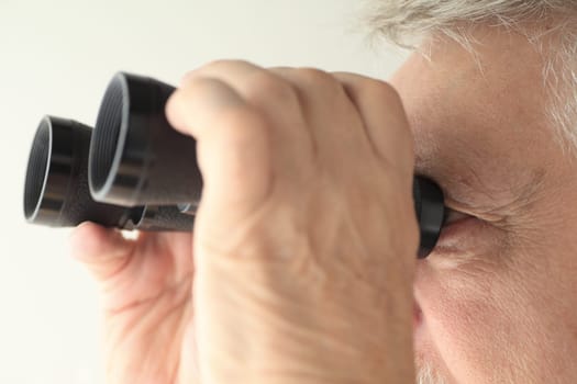 An older man looking through an old pair of binoculars