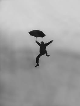 boy flying with an umbrella on a cloudy sky backgroung