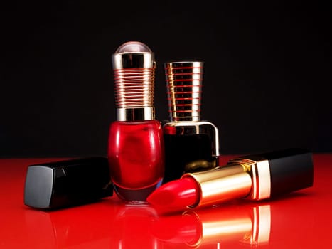 Red listick and nail polish shot over reflective background