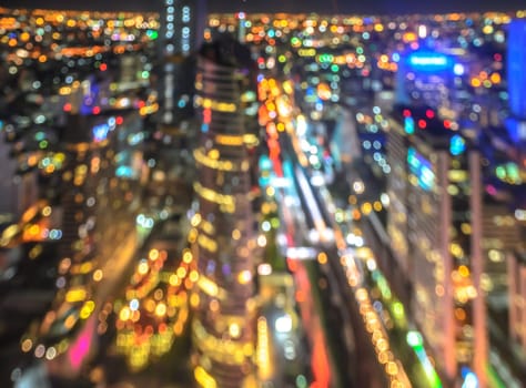 Colorful aerial view of cityscape illuminated at night. Blur abstract background image