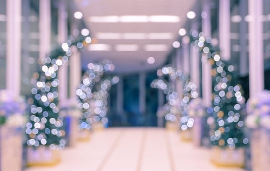 Defocused office, hotel lobby or shopping mall building indoor background with Christmas light illuminated on tree
