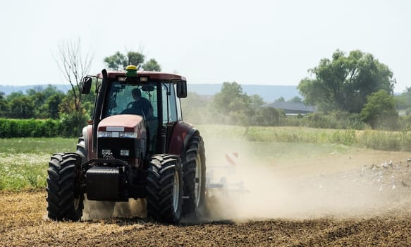 Tractor swirls dust during soil cultivation