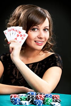 Young woman holding gambling chips on black background