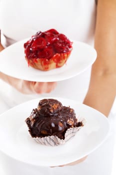 Young woman with two cakes - one with fruits and the other with chocolate