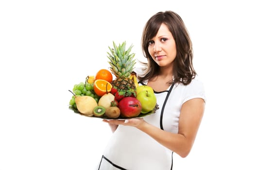 Young woman holding a tray with fresh fruits - apples, pears, grapes, pineapple, oranges, kiwi, strawberries and others.