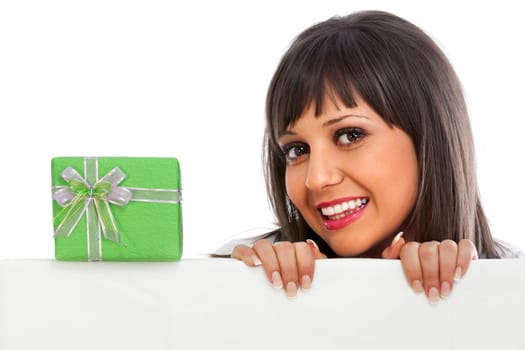 Young woman with christmas gift behind white billboard
