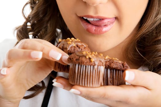 Young woman with chocolate muffin, close up of her mouth licking