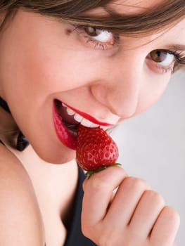 Young woman eating strawberry
