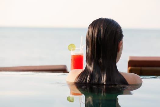 Young woman drinking Mai Thai Cocktail at the pool in a family hotel in Ko Samui, Thailand