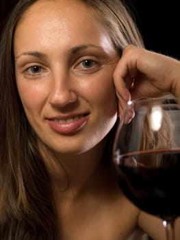 Portrait of young woman with wine glass on black