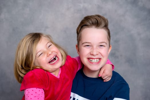 brother and sister together in front of gray background