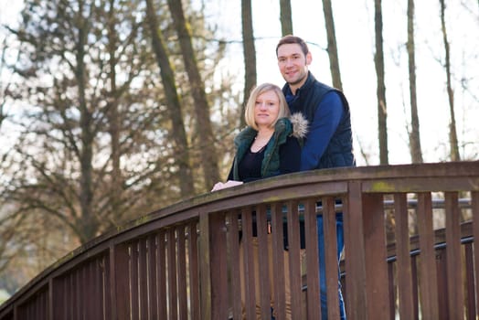 young blond woman with her husband in the parkon the bridge