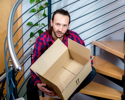 young man sitting in corridor with a empty box