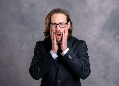 portrait of a young amazed business man in black suit
