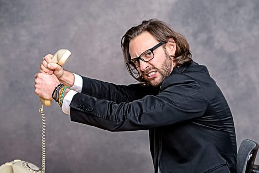 young angry businessman is choking his phone