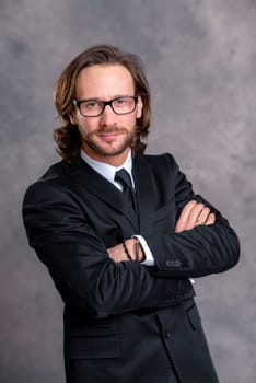 portrait of a young business man in black suit in front of gray background