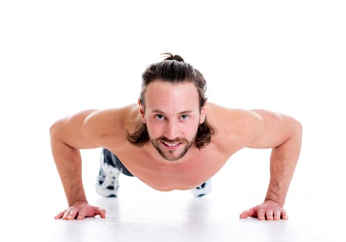young man doing press-up in front of white background