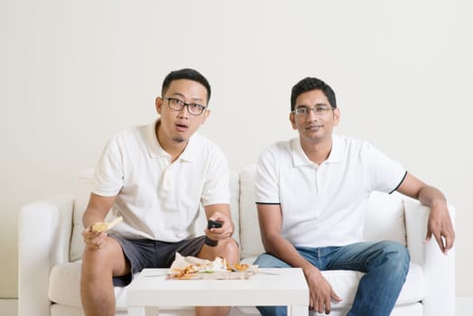 Male friends watching live sport game at home.