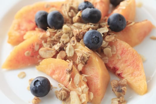 Fresh peach slices and blueberries sprinkled with granola