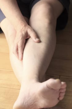A man on the floor puts a hand on his sore calf.