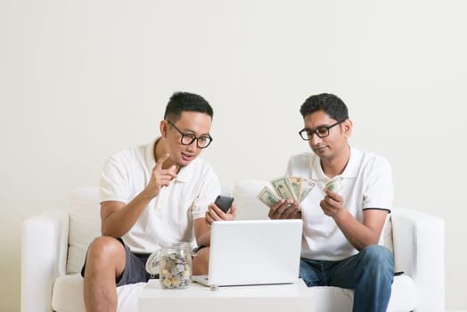 Asian men working from home. Young guys counting cash with partner, earning money from their successful online business.