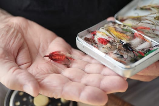 A man with a box of fly fishing flies, one in his hand