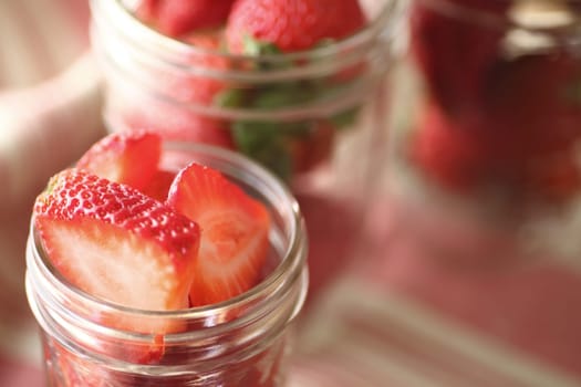 Canning jars with whole and sliced fresh strawberries with copy space