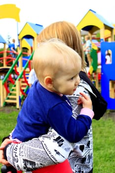 Mom carries her daughter in her arms on the playground