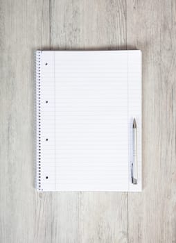 an empty notepad and a ballpoint pen lie on a white wooden background